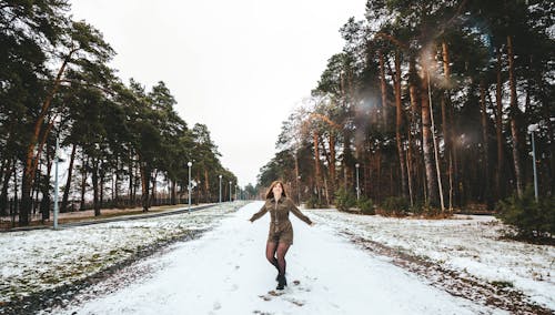 A Woman in a Romper Standing on a Snow Covered Road