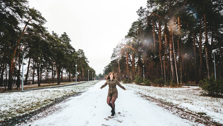 A Woman In A Romper Standing On A Snow Covered Road