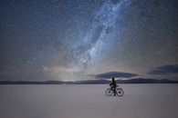 Man Riding Bicycle on Snow Covered Ground during Night Time
