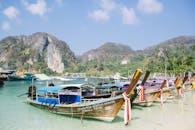 晴朗的天空下，色彩缤纷的长尾船停靠在热带山脉旁，构成完美的度假场景