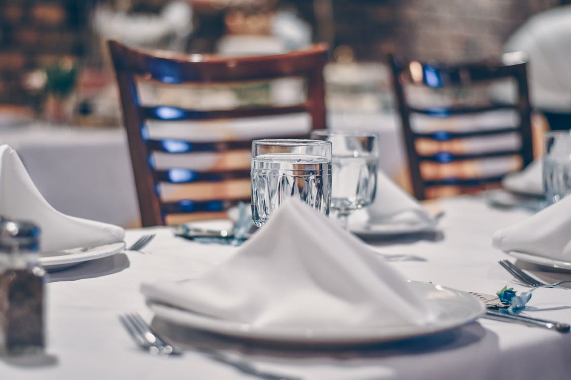 Free Depth of Field Photo of Clear Drinking Glass on White Table Near Plate Stock Photo