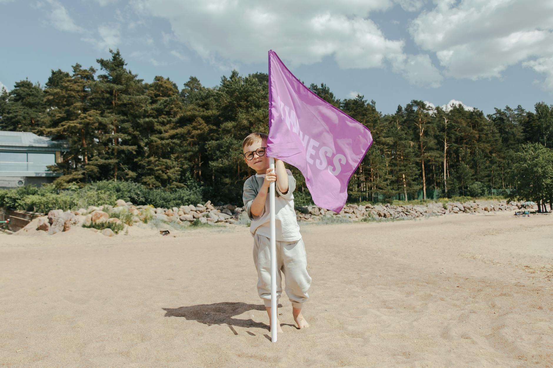A Boy Holding a Pink Flag With The Word Kindness on It