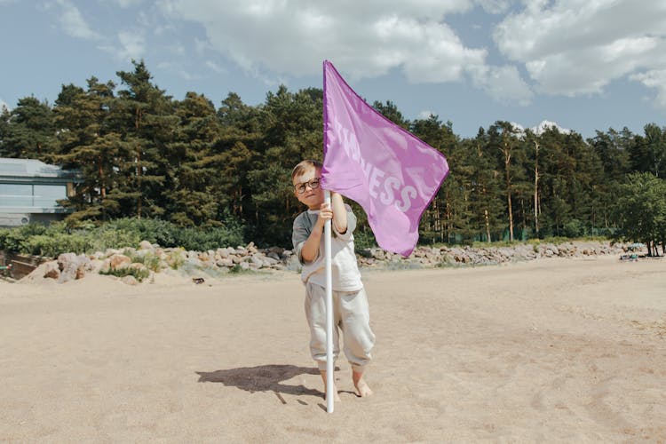 A Boy Holding A Pink Flag With The Word Kindness On It