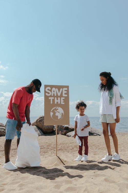 Free Family volunteering on a beach cleanup to save the planet. Perfect for Earth Day themes. Stock Photo