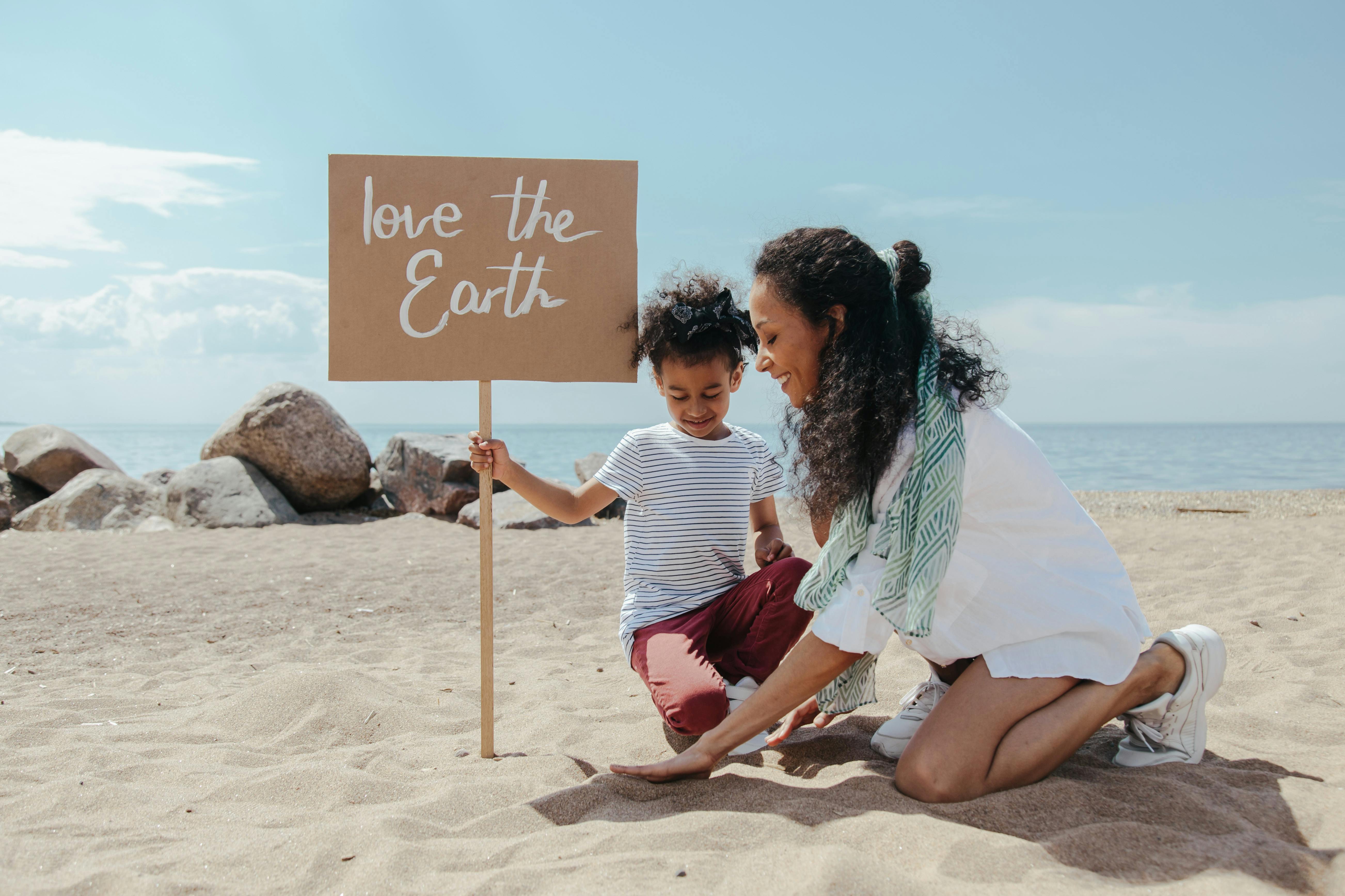 a woman and a child holding a poster on the beach