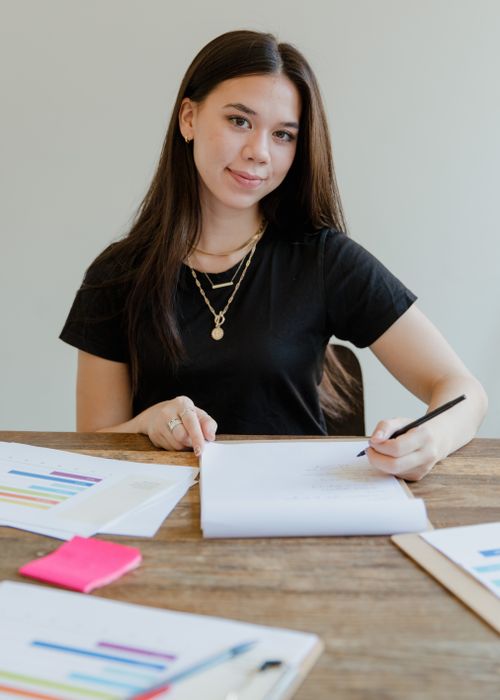 Free Portrait of an Asian woman writing with documents in an office setting. Stock Photo