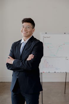 Smiling businessman in office with graphs in the background, showcasing success and professionalism.