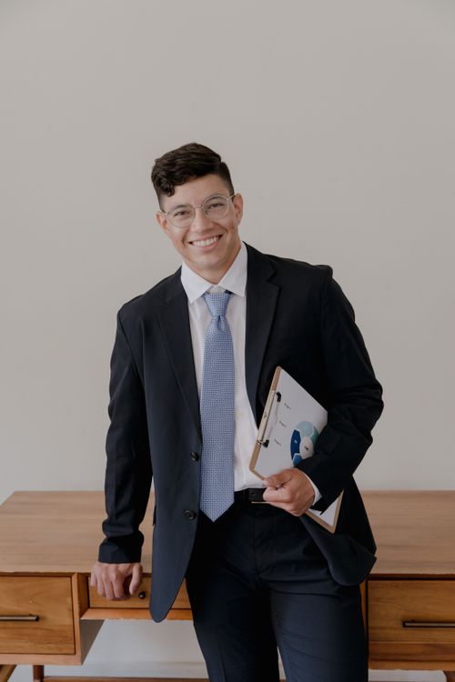 Free Confident businessman in a black suit smiling, holding clipboard indoors. Stock Photo