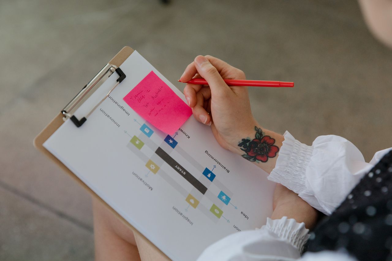 close up of a person using a red pen on a sticky note attached to a ch