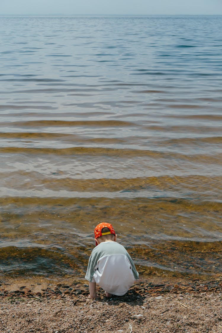 Toddler Squatting On Beach Shore