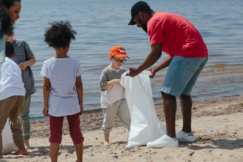 Free Volunteers and children participate in a beach cleanup to promote environmental awareness. Stock Photo