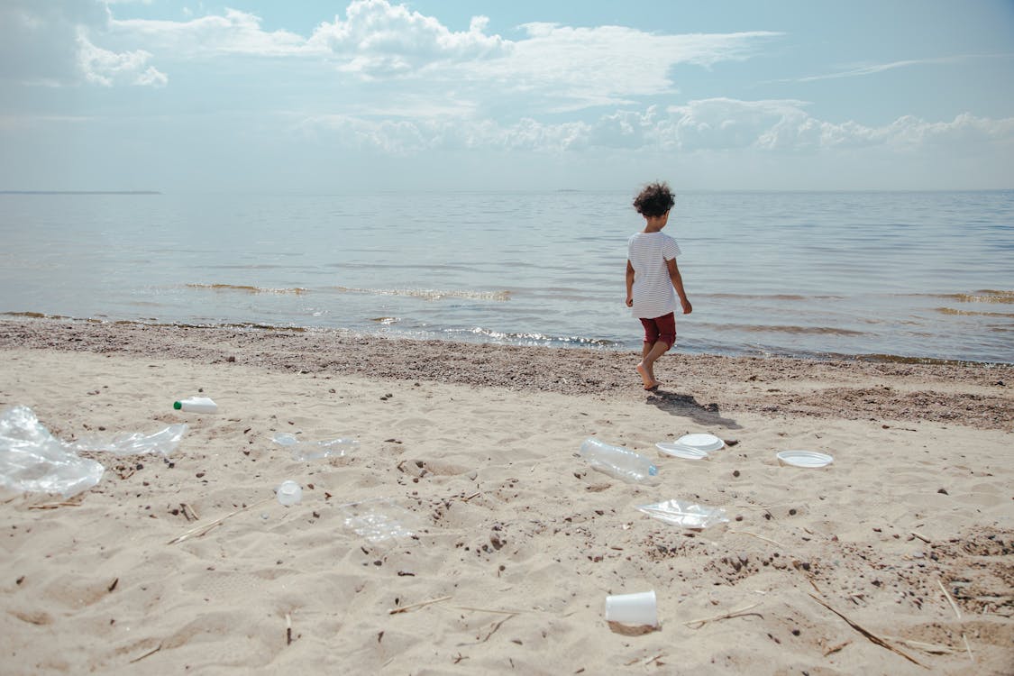 Boy walking among plastic waste on the beach