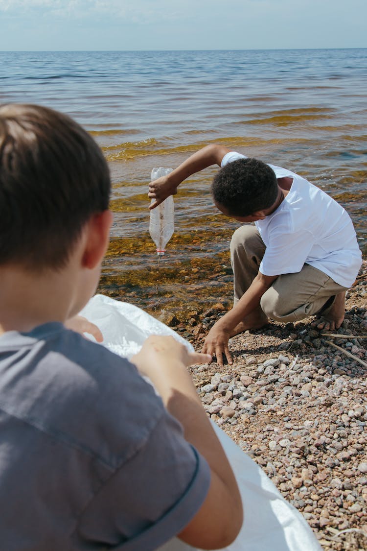 Two Boys Cleaning Up Trash At The Beach