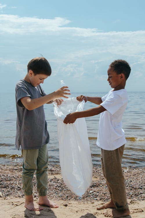 Photo of Boys Collecting Plastic Trash on a Seashore