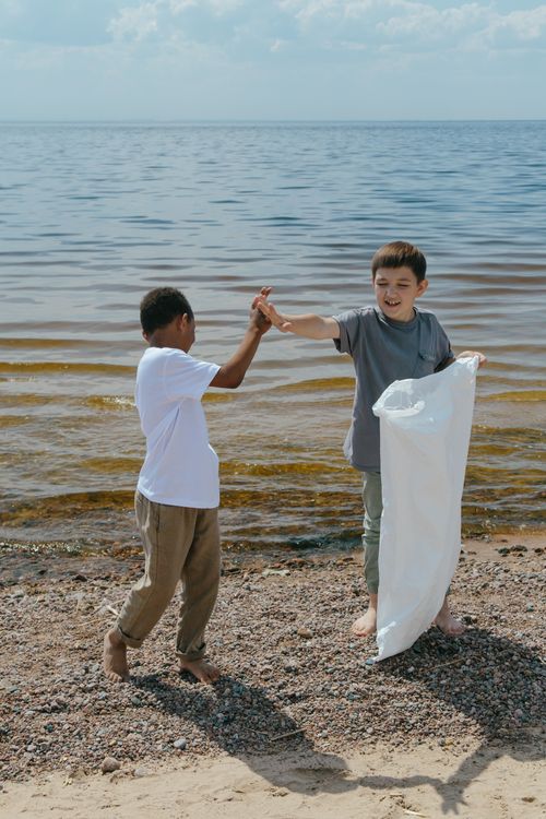 Free Two boys enthusiastically clean up litter on a beach promoting environmental awareness. Stock Photo