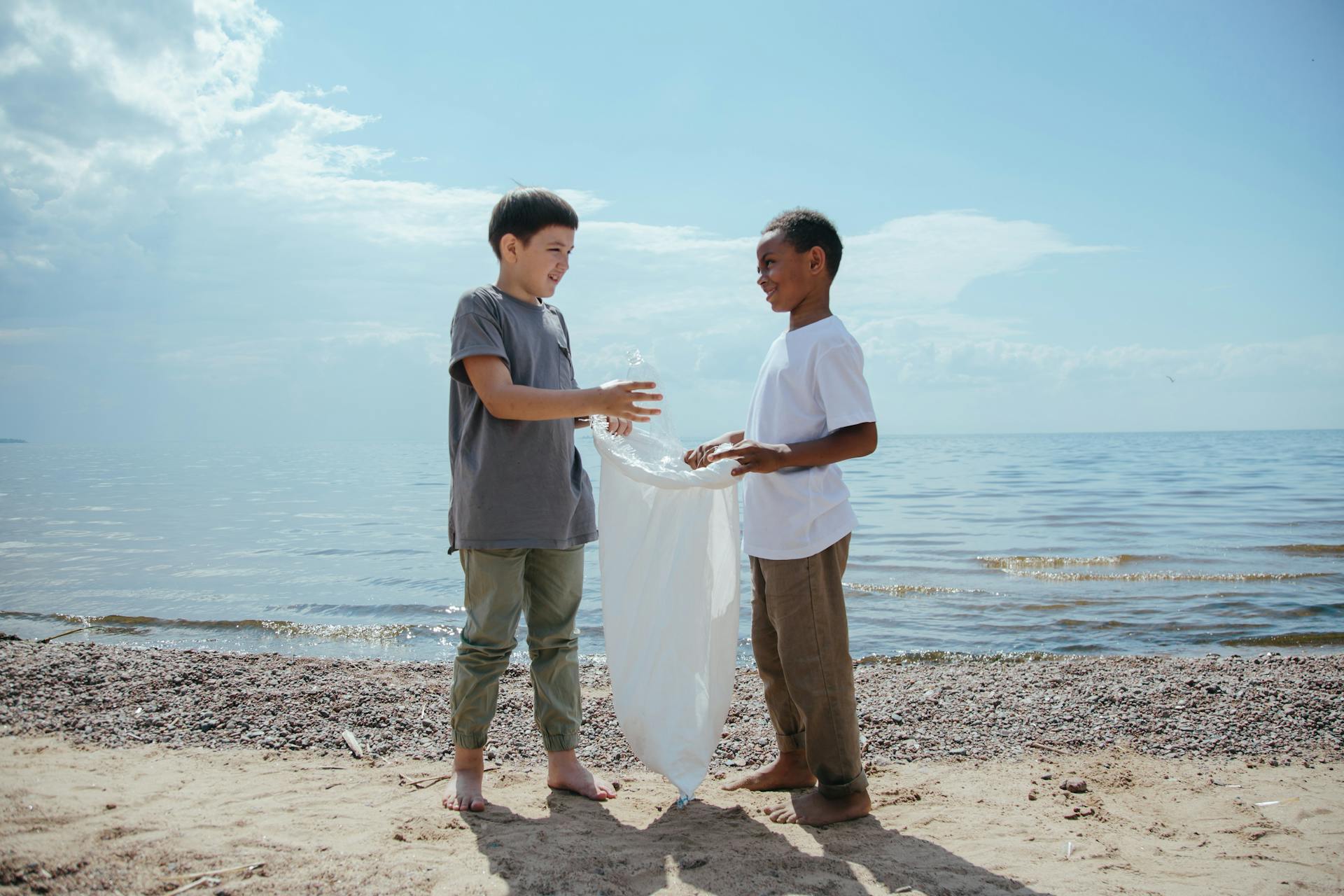 Boys engaged in a beach cleanup, collecting plastic trash in a team effort.