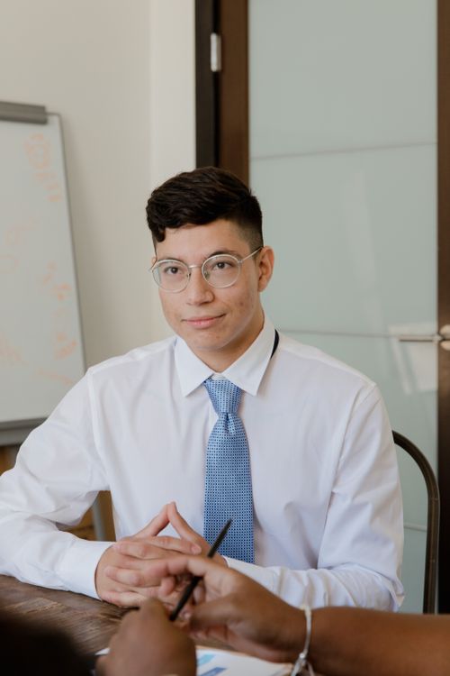 Free A young professional in a business meeting wearing glasses and a blue tie in an office setting. Stock Photo