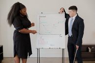 Man in Black Suit Holding White Board