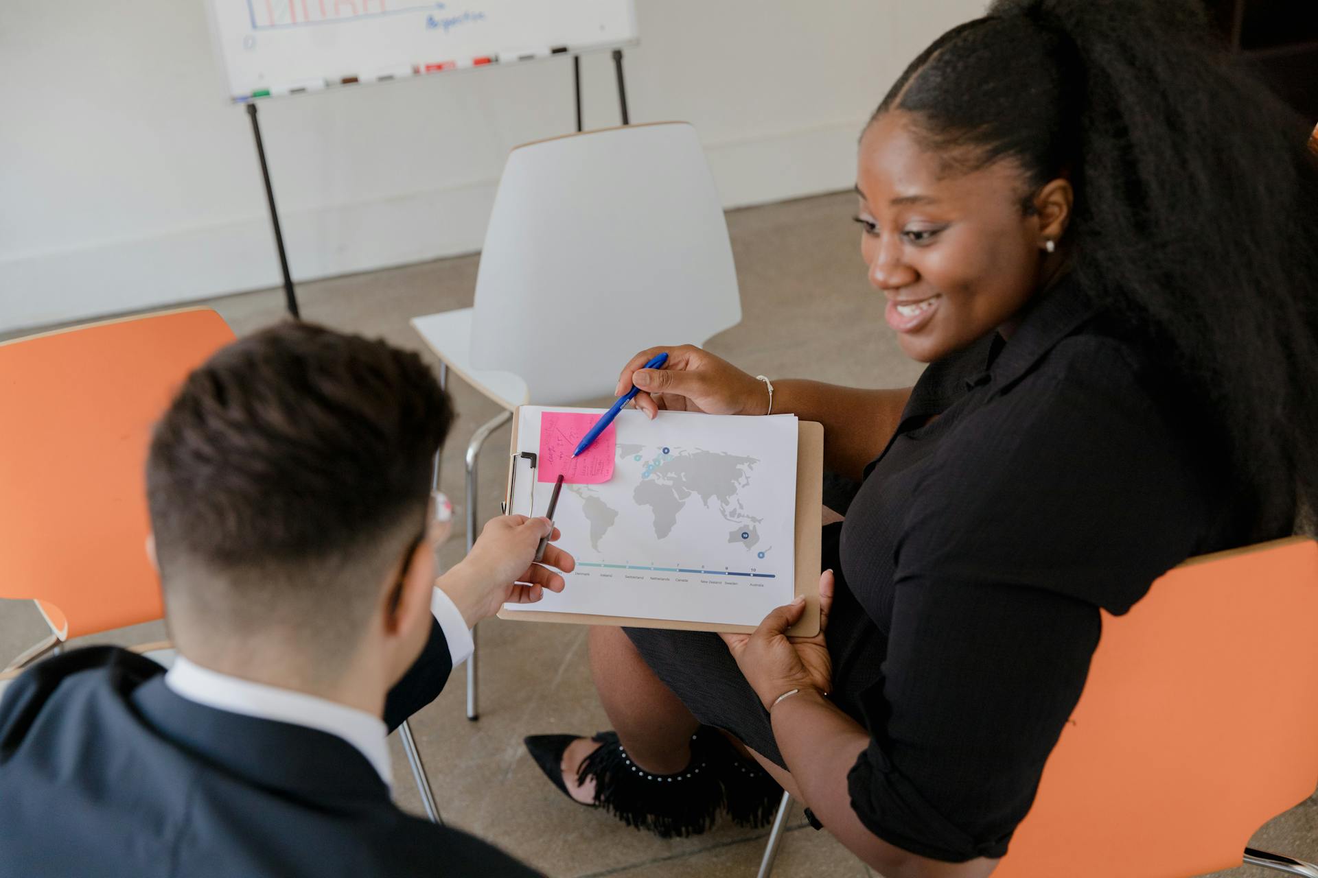 Two colleagues discussing a world map in an office setting, promoting teamwork and planning.