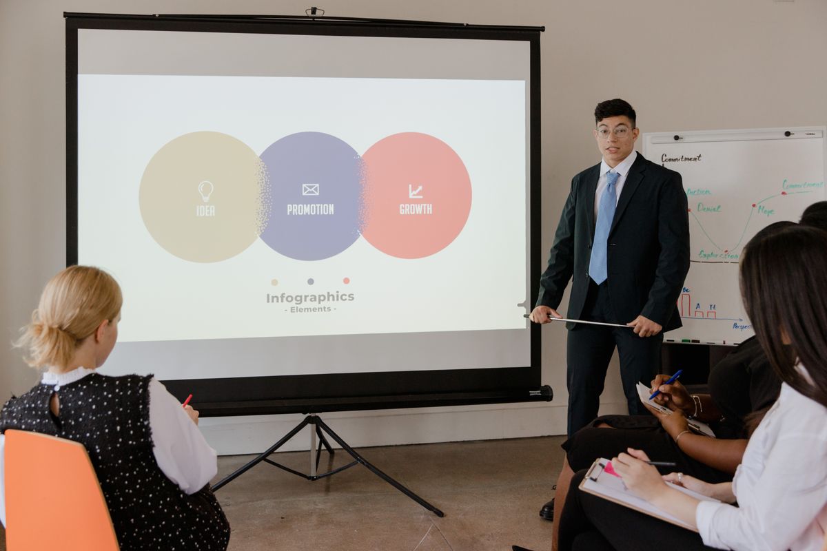 A business team views slide infographics projected on a screen during a presentation