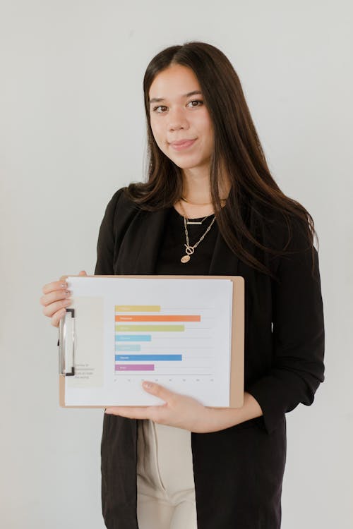 Young Woman in Black Coat Holding a Clipboard with Chart and Data