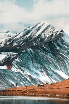 Captivating view of the Himalayas with snowy peaks and hikers by a serene lake in Nepal.