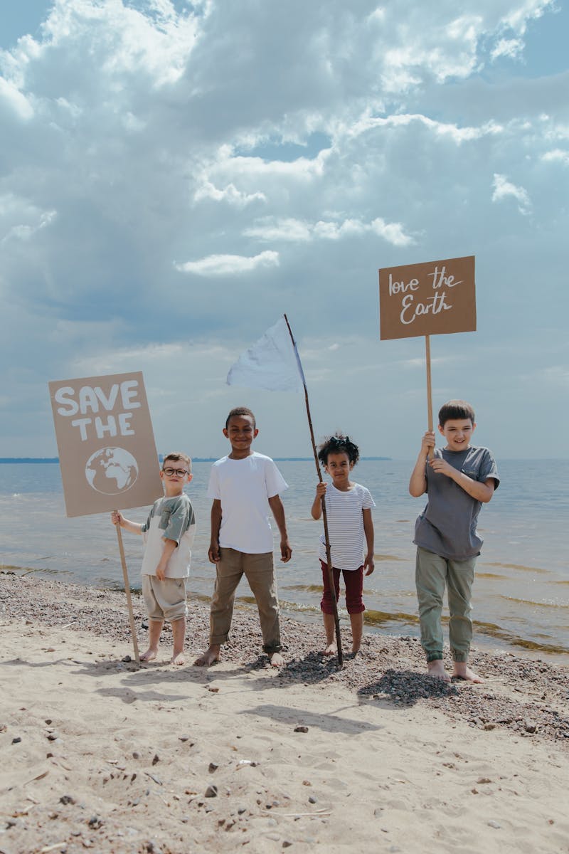 Children Standing at the Seashore while Holding Signages