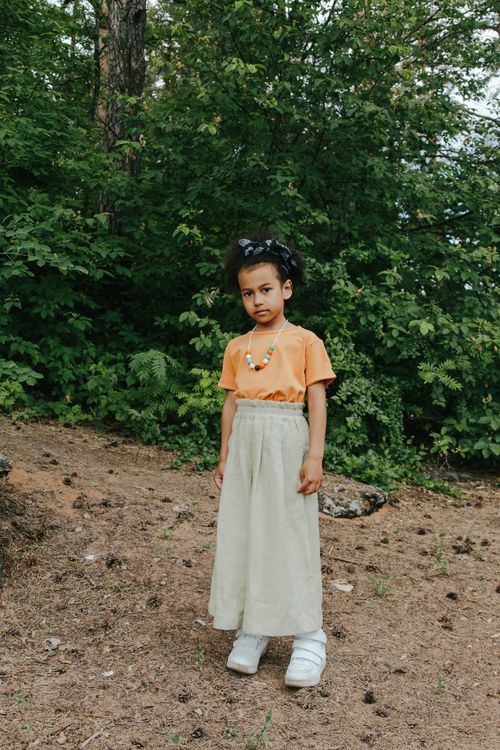 Free Portrait of a fashionable young girl standing confidently outdoors in a forest. Stock Photo