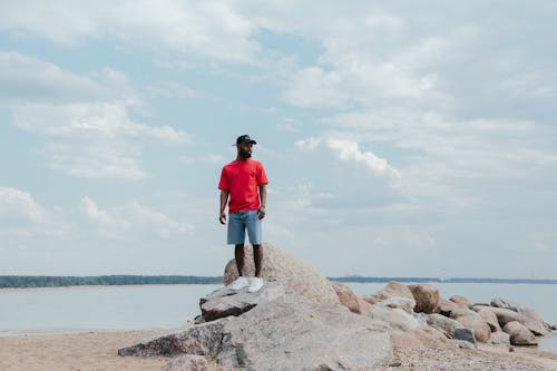 Man Standing on Boulders near the Sea