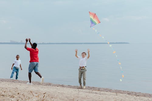 A Man  and Two Boys Flying Kite by the Seashore