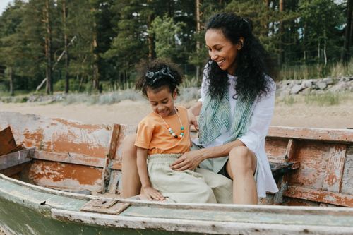 Free Warm family moment of mother and daughter smiling together in an old fishing boat by the forest. Stock Photo