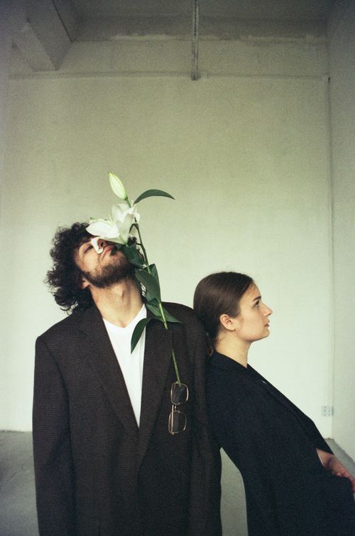Free Artistic image of a man holding a flower and a woman leaning, set in a minimalist room. Stock Photo