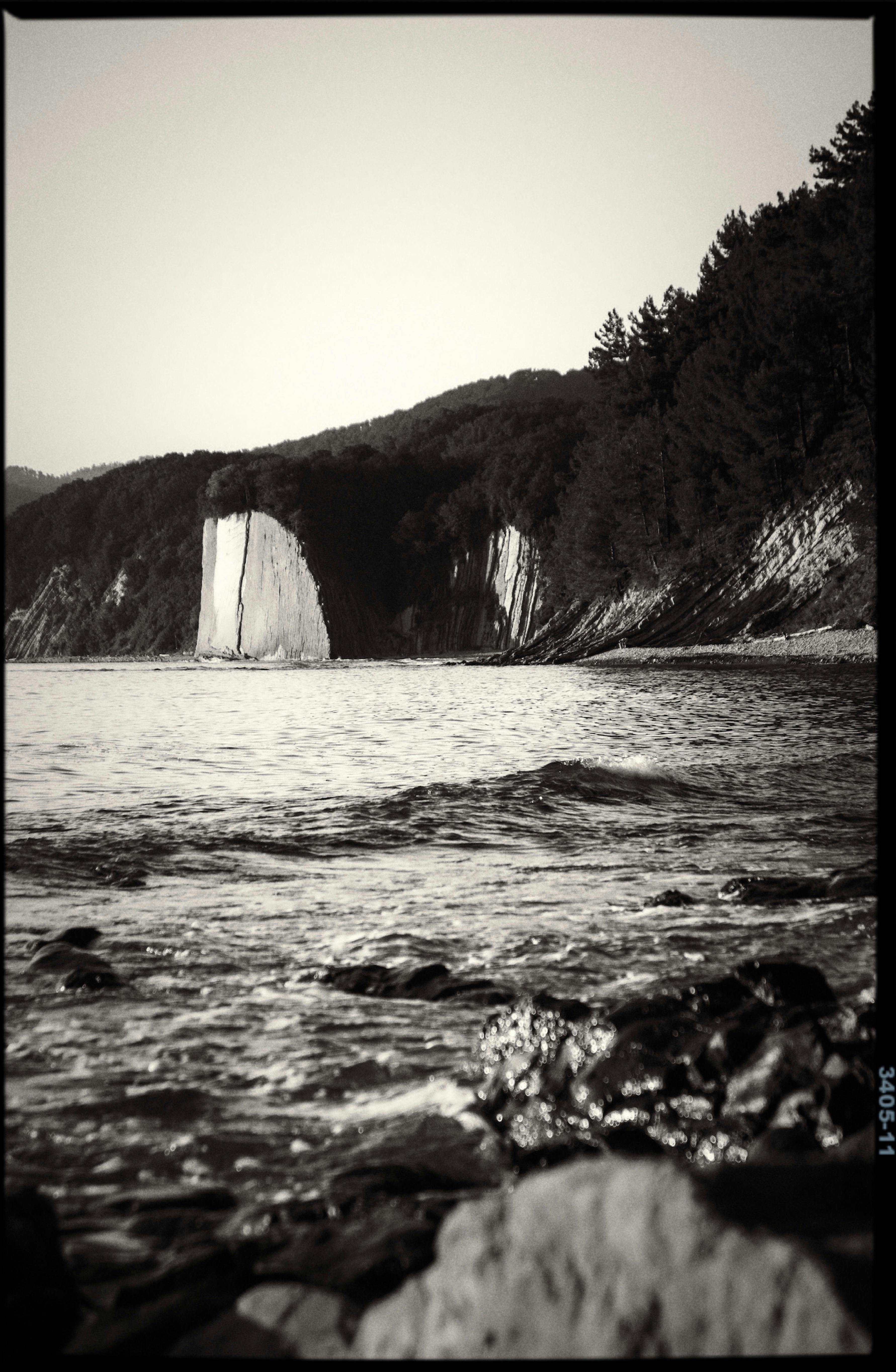 Black and white photo of a scenic coastline with cliffs and sea.
