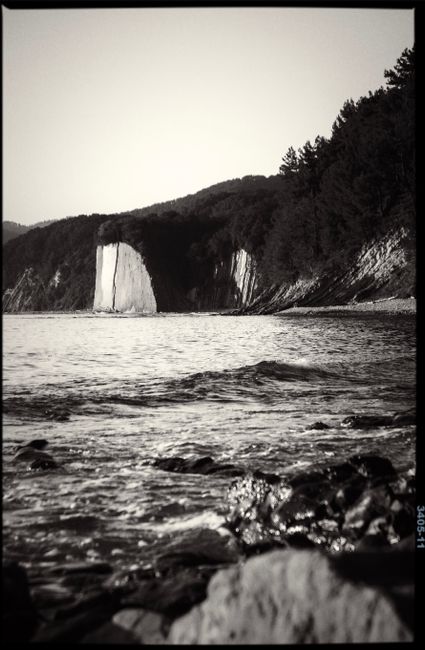Black and white photo of a scenic coastline with cliffs and sea.