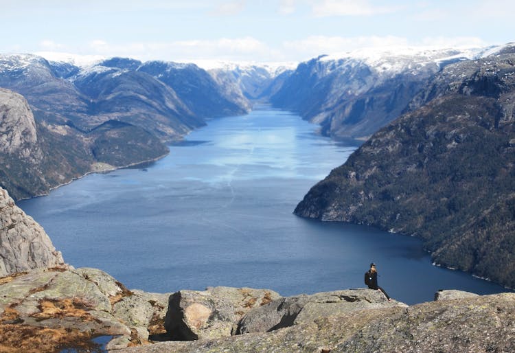 Unrecognizable Hiker Contemplating Dramatic Fjord On Rocky Mountain Peak