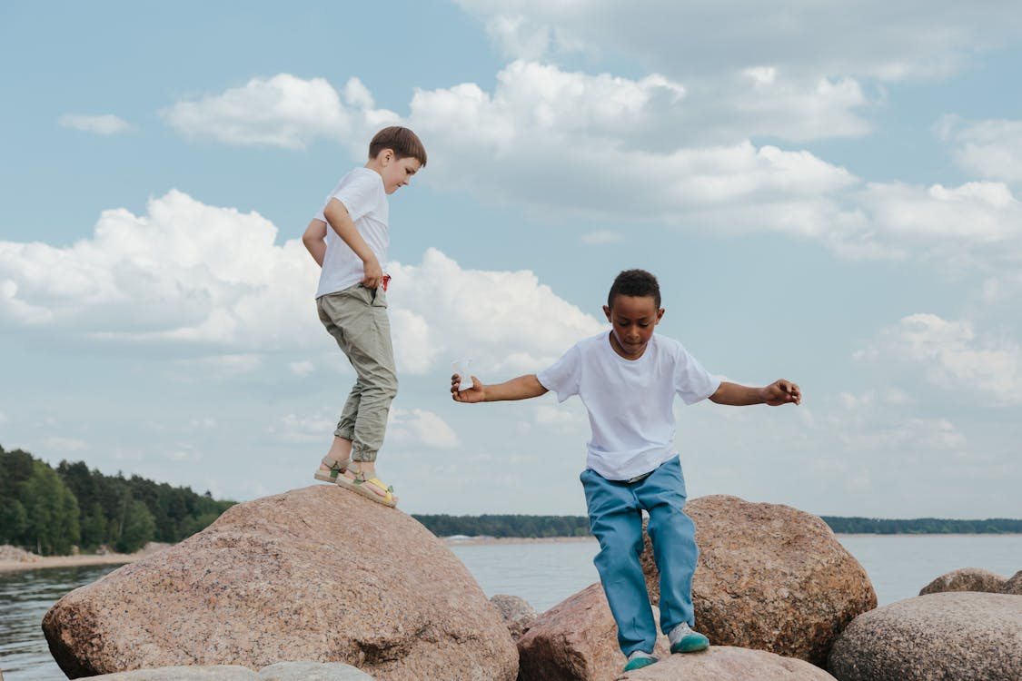 Kids in White Shirts Playing while Standing on the Rocks