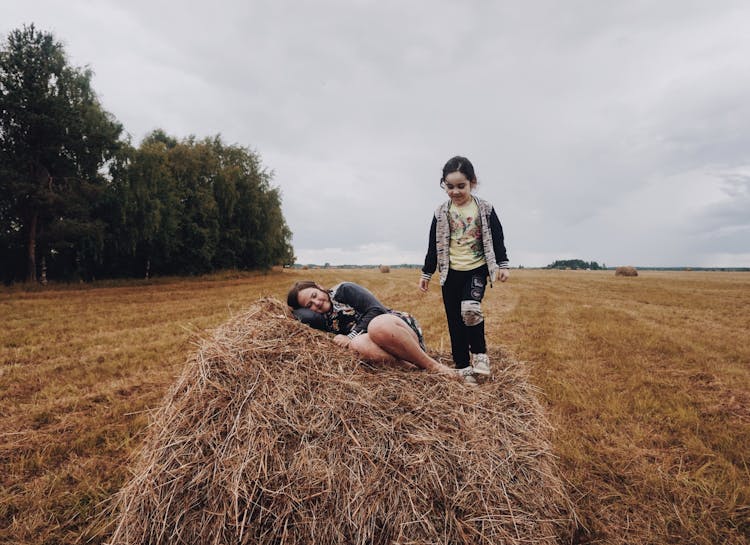 Girls Playing On Hay On Field