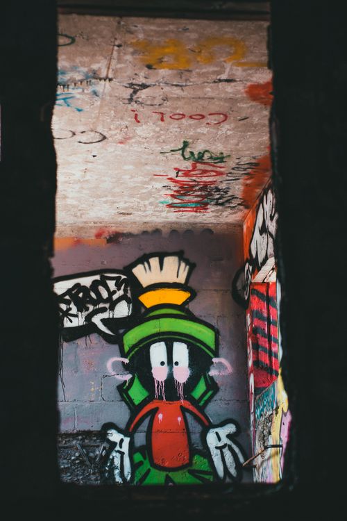 Free Vibrant street art depicting a cartoon character on a graffiti-filled urban wall. Stock Photo