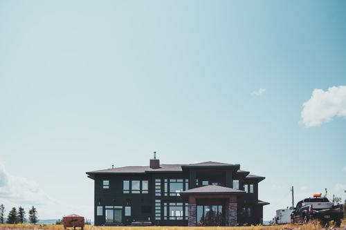 Free A modern suburban house stands under a bright blue sky, illustrating contemporary architecture and tranquil living. Stock Photo