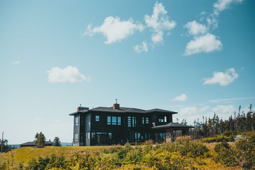 Free Stylish black modern house in a serene countryside with a bright blue sky. Stock Photo