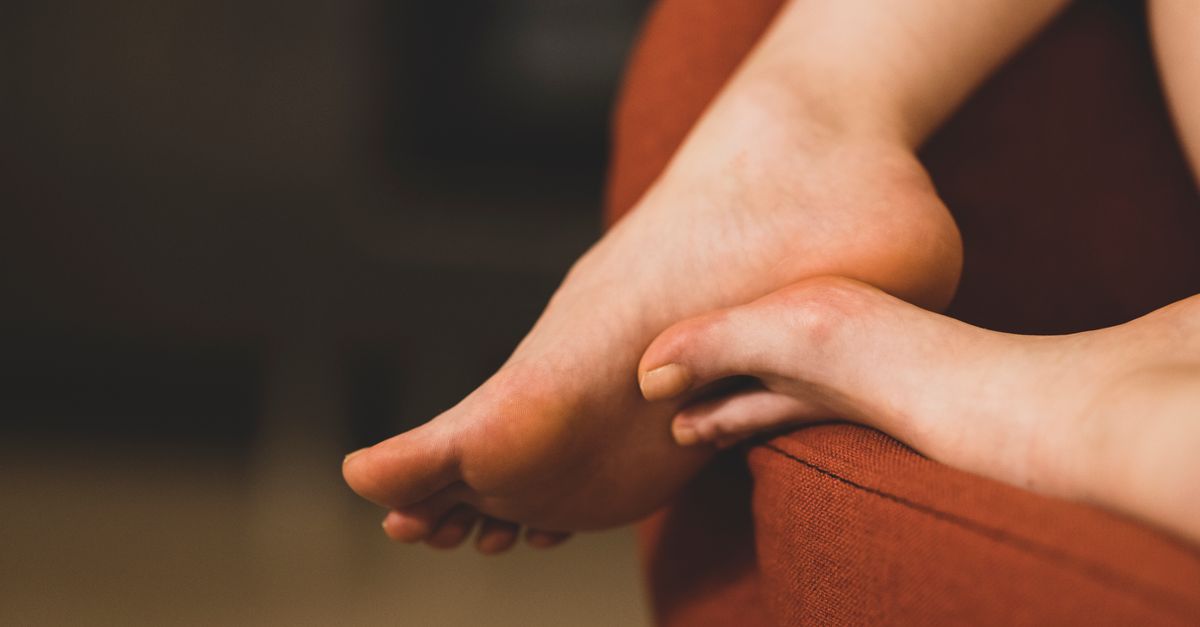 A serene close-up of feet resting on a cozy red sofa indoors, depicting relaxation.