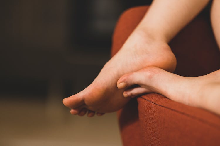 Person's Feet On Red Sofa