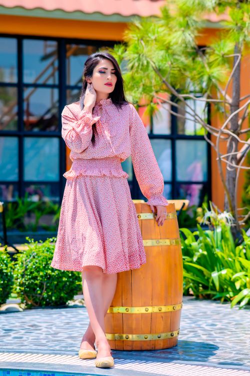 Free Elegant woman in a pink dress posing by a wooden barrel outdoors. Stock Photo