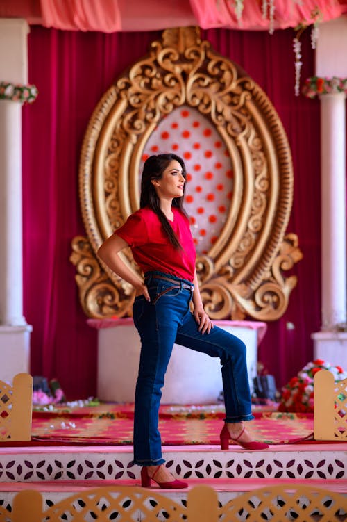 Free Woman in Red Shirt and Blue Denim Jeans Standing Stock Photo