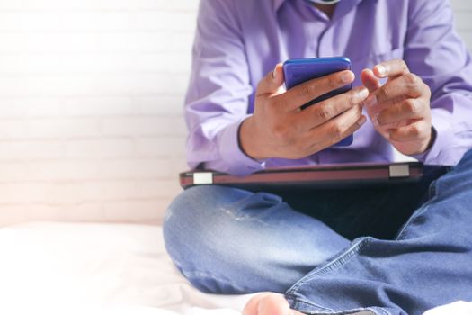 Casual setting with a man using a smartphone indoors, focusing on technology and relaxation.