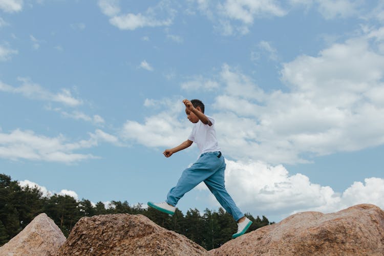 A Boy Jumping Over The Rocks