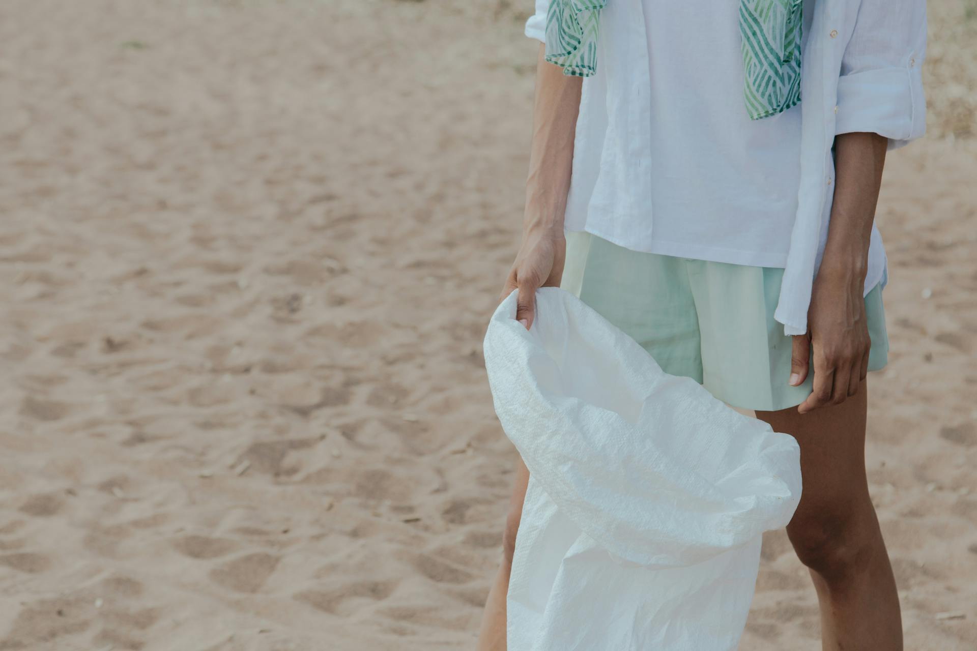 A Person in White Shirt and Green Shorts Holding White Sack