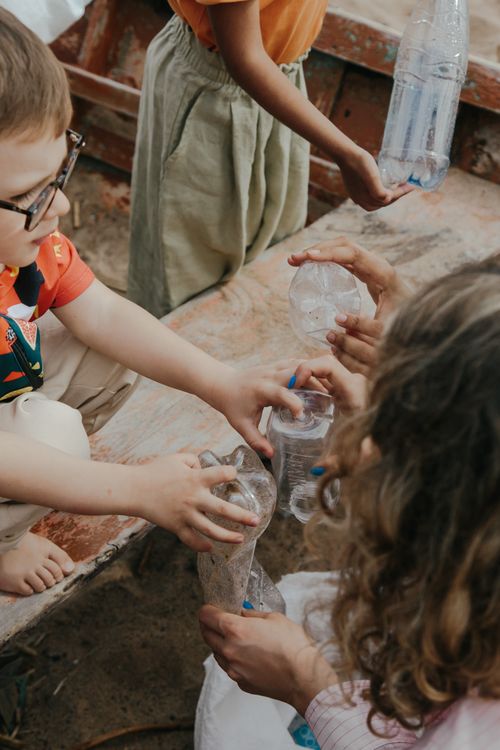 Free Young volunteers collect plastic bottles for recycling, learning teamwork and environmental responsibility. Stock Photo