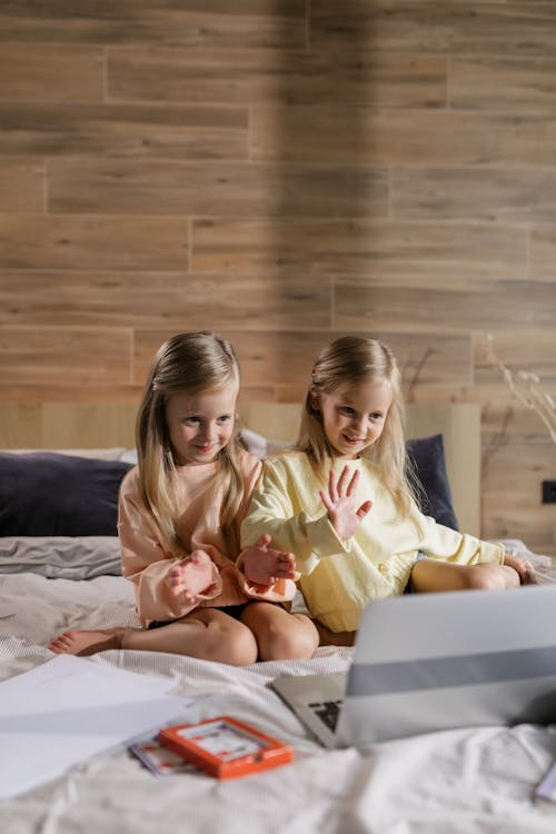 Two Girls Having an Online Class while Sitting on the Bed