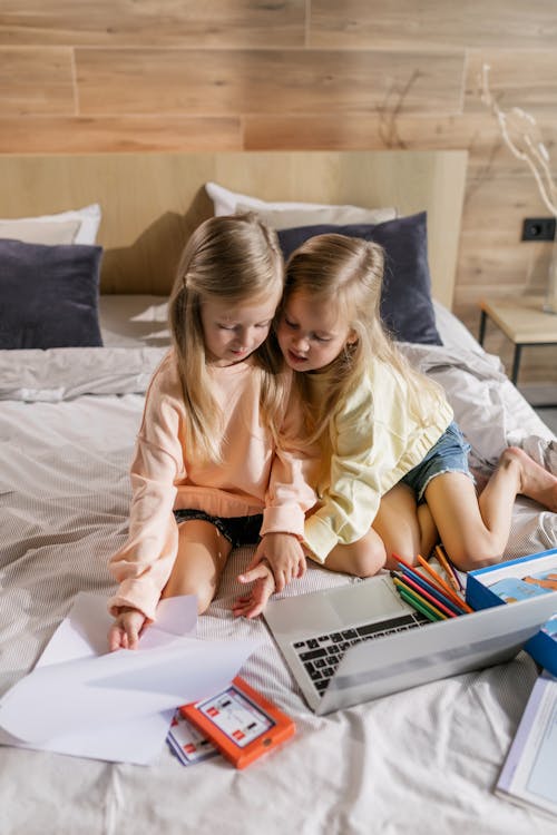 Two Girls Having an Online Class while Sitting on the Bed